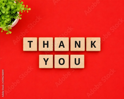 Thank You Message Made from Wooden Letter Blocks on Bright Red Background with Green Plant and Copy Space. 