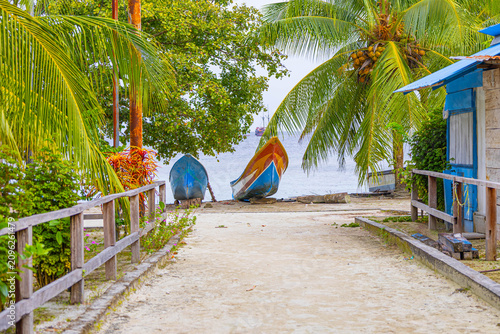 Schilderij op canvas The road to the beach with boats under palm tree
