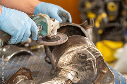 Quadro su tela Mechanic grinding a car catalytic converter or exhaust pipe system with an angle grinder