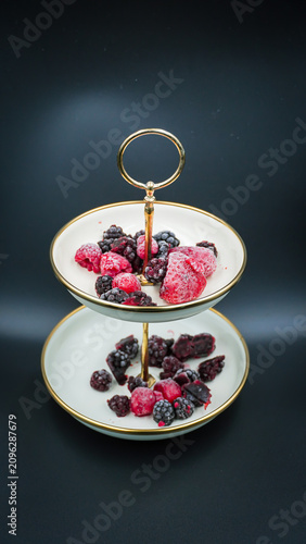 Frozen Mixed Berries on an Elegant Two-Tiered Serving Tray Against a Dark Background