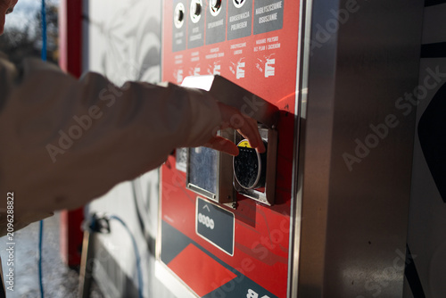 Hand pressing button on automated vending machine at manual carwash station.