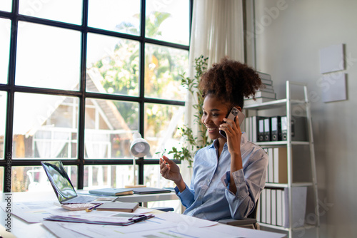 Confident businesswoman talking on phone in modern office. Smiling and enjoying conversation, successful professional communication.