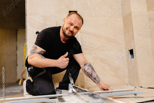 Tiler cutting tile with manual cutter in bathroom