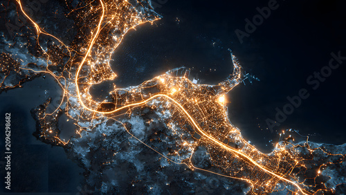Aerial night view of an urban coastal metropolitan area illuminated by extensive city light networks and winding infrastructure patterns