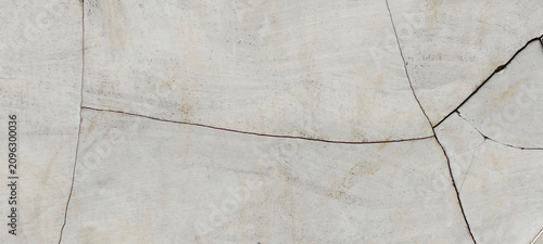 A close-up photo of a severely cracked gray cement plaster surface.
