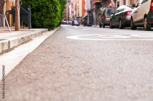 Low angle view of empty asphalt road surface with painted speed limit 30 road-marking on a quiet city street slope in summer