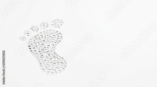 Water droplets forming footprint shape on white surface, symbolizing environmental impact and sustainability