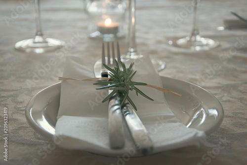Elegant place setting with a sprig of rosemary on a formal table
