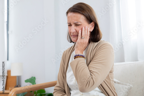 Obraz na plátně Mature woman touching her cheek suffer from toothache