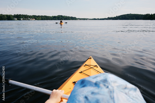 pov of child in kayak on lake holding oar in her hand