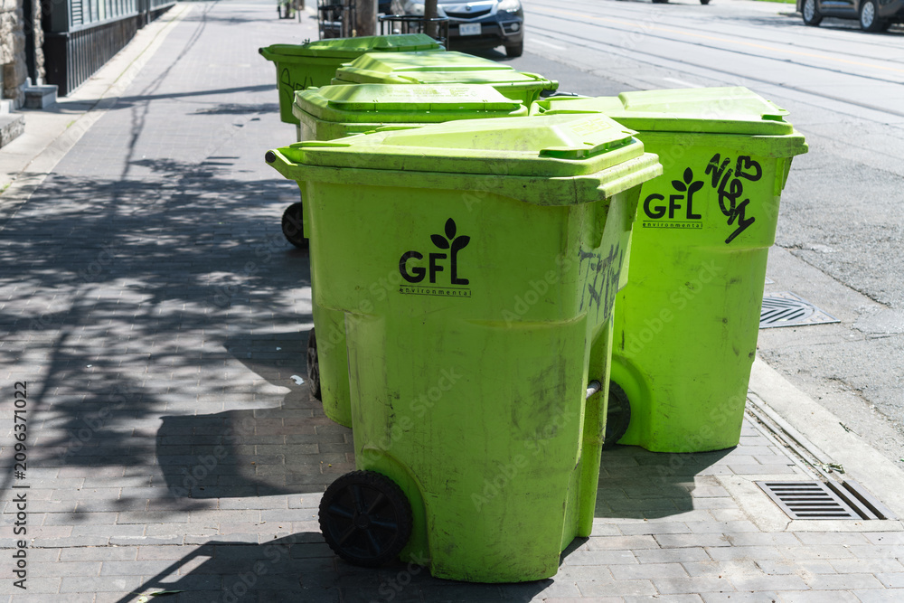 Obraz premium grungy GFL (Green For Life Environmental) recycling bins on a sidewalk in Toronto