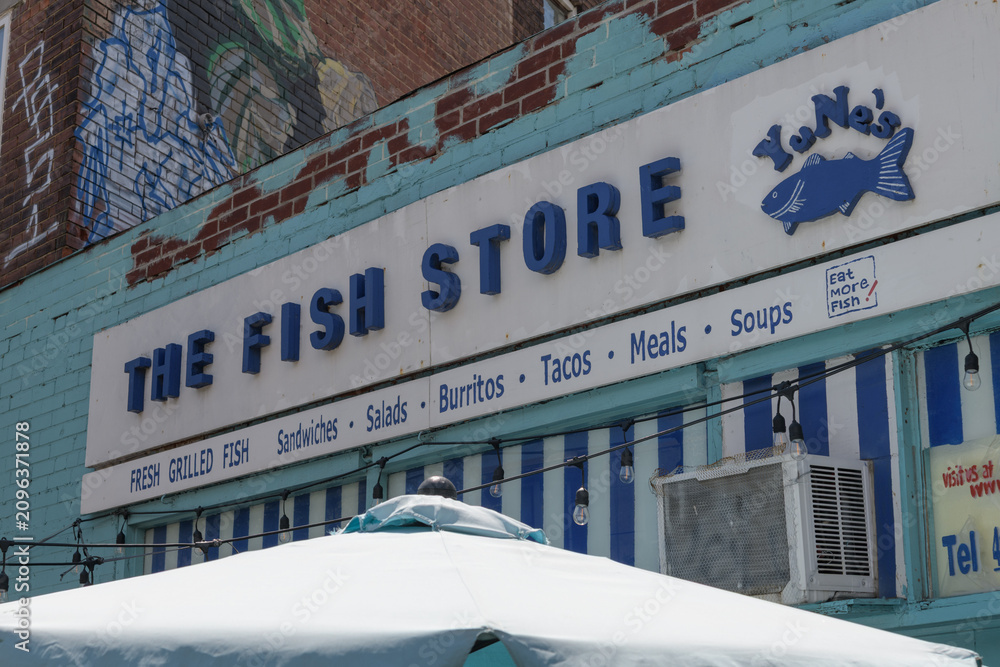 Obraz premium exterior building facade and sign of The Fish Store & YuNes' Sandwiches located at 657 College St, Toronto