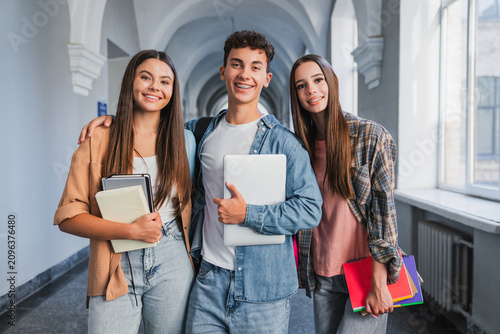 Portrait of high school students looking at camera in school corridor, classmates standing together, education, teamwork, friendship, learning and student life concept
