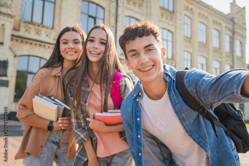 Teenage students taking selfie near college campus, young classmates having fun outside educational building, friendship, youth, learning and school life concept