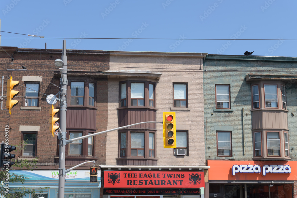 Fototapeta premium historic commercial block (with apartments above) on St Clair Av W including signs of Yummi Café Laundromat, The Eagle Twins hamburger restaurant, and Pizza Pizza, Toronto
