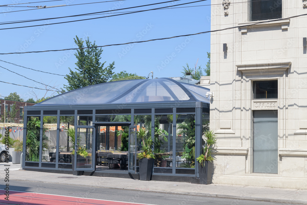 Fototapeta premium glass-enclosed rear patio / garden dining and detail of heritage Bank of Nova Scotia building - now DaNico, a restaurant, located at northeast corner of Bathurst St and College St, Toronto