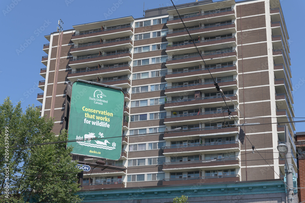 Obraz premium rooftop billboard featuring ad for Ducks Unlimited Canada with apartment building and sky, Toronto