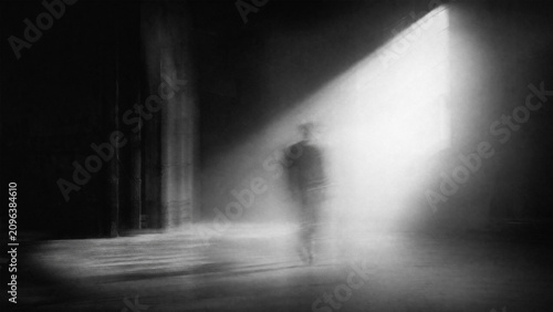 Mysterious solitary figure walking into a dramatic spotlight beam through dark foggy space blackandwhite image