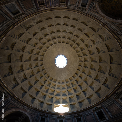 Wide angle panoramic view of the ancient coffered dome of the Pantheon with oculus and light beam reflection in Rome, Italy
