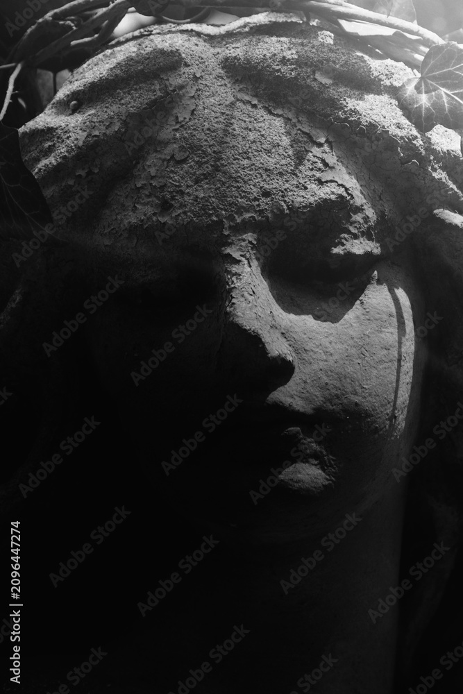 Obraz premium A weathered cemetery angel emerges from darkness, reminding us that even in grief, hope quietly endures.