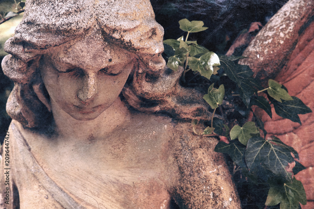 Fototapeta premium Ancient cemetery angel statue surrounded by ivy. Symbol of remembrance, faith, hope, eternal peace and divine protection.