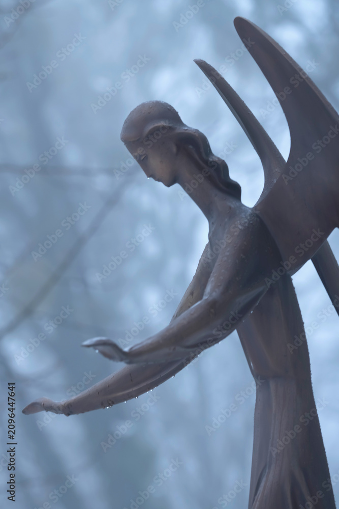 Obraz premium Ancient angel statue standing in the rain with outstretched hands. A symbol of protection, hope, faith and compassion through life's darkest moments.