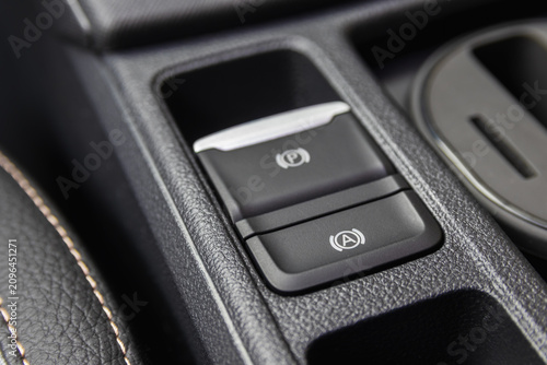 Close-up of an electronic parking brake and auto hold button on a modern car center console