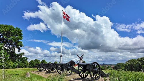 Historic cannons with the Danish flag at Dybbol Banke in front of Dybbol Mill near Sonderborg beneath a blue sky