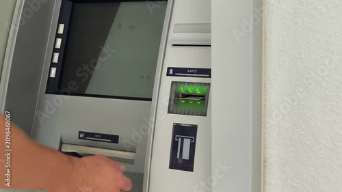 Close-up of a person inserting a credit card into an ATM slot for banking transaction