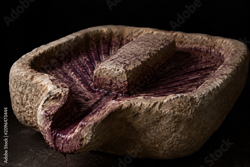 An ancient stone winepress basin with deep purple grape residue stains.