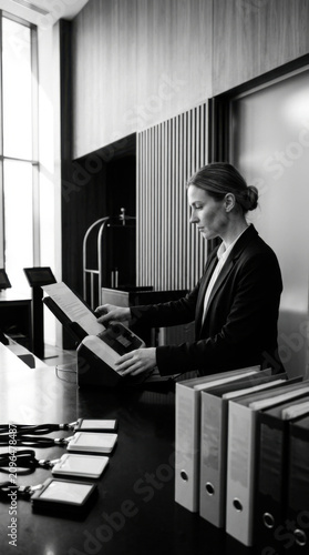 Professional Woman At Reception Desk Organizing Documents With Files