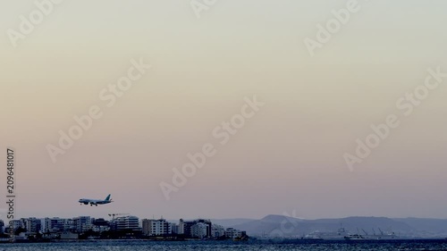 A plane is landing while flying low over the sea. Cyprus Island, tourist boats, Mediterranean Sea.