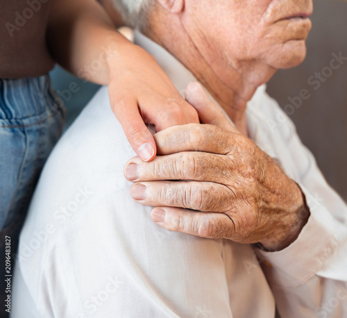 Konstfotografi A young woman's hand holds the hand of a senior adult man, comforting or sympathizing with him