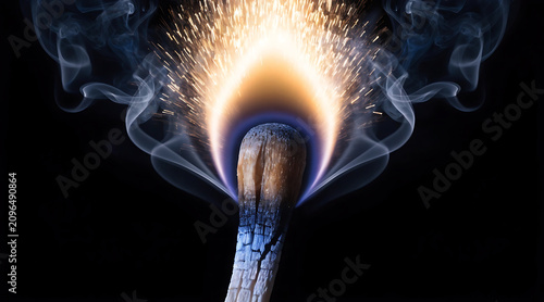 Burning match closeup with smoke and sparks, dramatic fire macro image of ignited wooden match