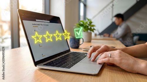 Person using laptop to submit online customer feedback with four star rating and checkmark feedback customer satisfaction checkmark business
