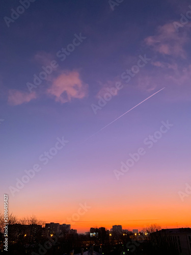 Colorful sunset sky over a city skyline with purple and orange hues.
