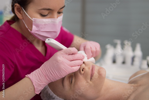 Quadro su tela Cosmetologist performing a professional facial skincare treatment on a woman usi