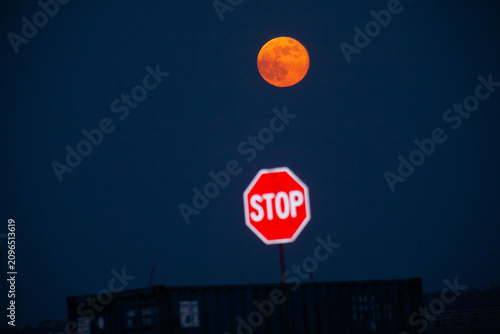 Foto Moon rises behind a stop sign.