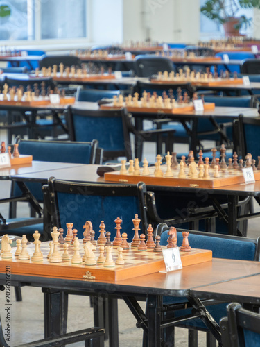 Obraz na płótnie Some chess boards with arranged pieces with a chess clock timer on the tables re