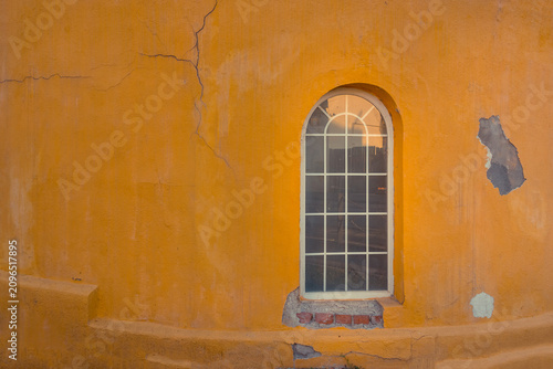 Canvastavla A rustic arched window set in a weathered orange wall with visible cracks
