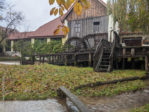 Foto Rustic wooden mill surrounded by autumn leaves and a gentle stream in a peaceful rural setting