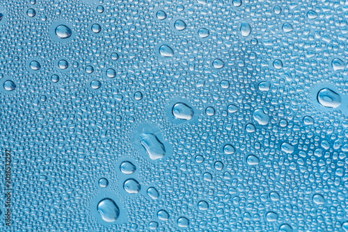 Obraz na plátně Close-up of clear water droplets on a smooth blue surface, creating a refreshing and textured pattern