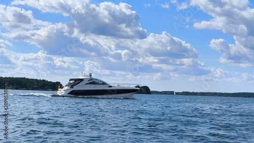 Modern motor yacht cruising fast on a lake on a sunny day with German flag on stern