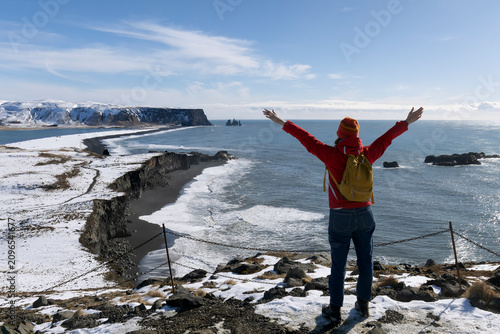 Fotografie A person standing along a stunning black sandy beach Reynisfjara and rocky terra