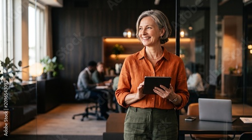 European businesswoman CEO using fintech tab application standing at workplace in office. Latin Hispanic mature professional business woman holding digital tablet for trading, looking at copy space