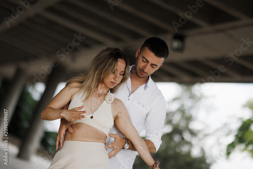 Couple practicing partner dance under a pavilion, intimate salsa rehearsal with instruction, connection and trust during romantic dance practice