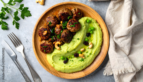 Overhead view of homemade meatballs served with creamy kohlrabi in a rich herb sauce and smooth potato and green pea mash. Garnished with sweet raisins and crunchy cashews, this rustic gourmet meal, 