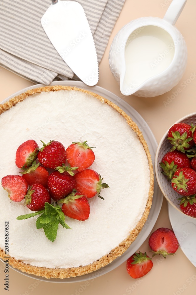 Obraz premium Yummy cheesecake with strawberries and milk on beige table, flat lay