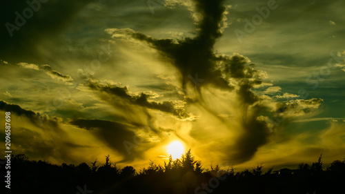 Foto Dramatic sunset in Maryland with dark, ominous storm clouds contrasting against a bright yellow white light source near the horizon