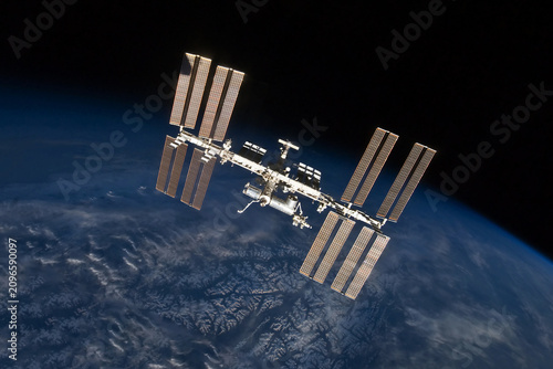 International Space Station floats above Earth's blue oceans and white clouds. Elements of this image furnished by NASA